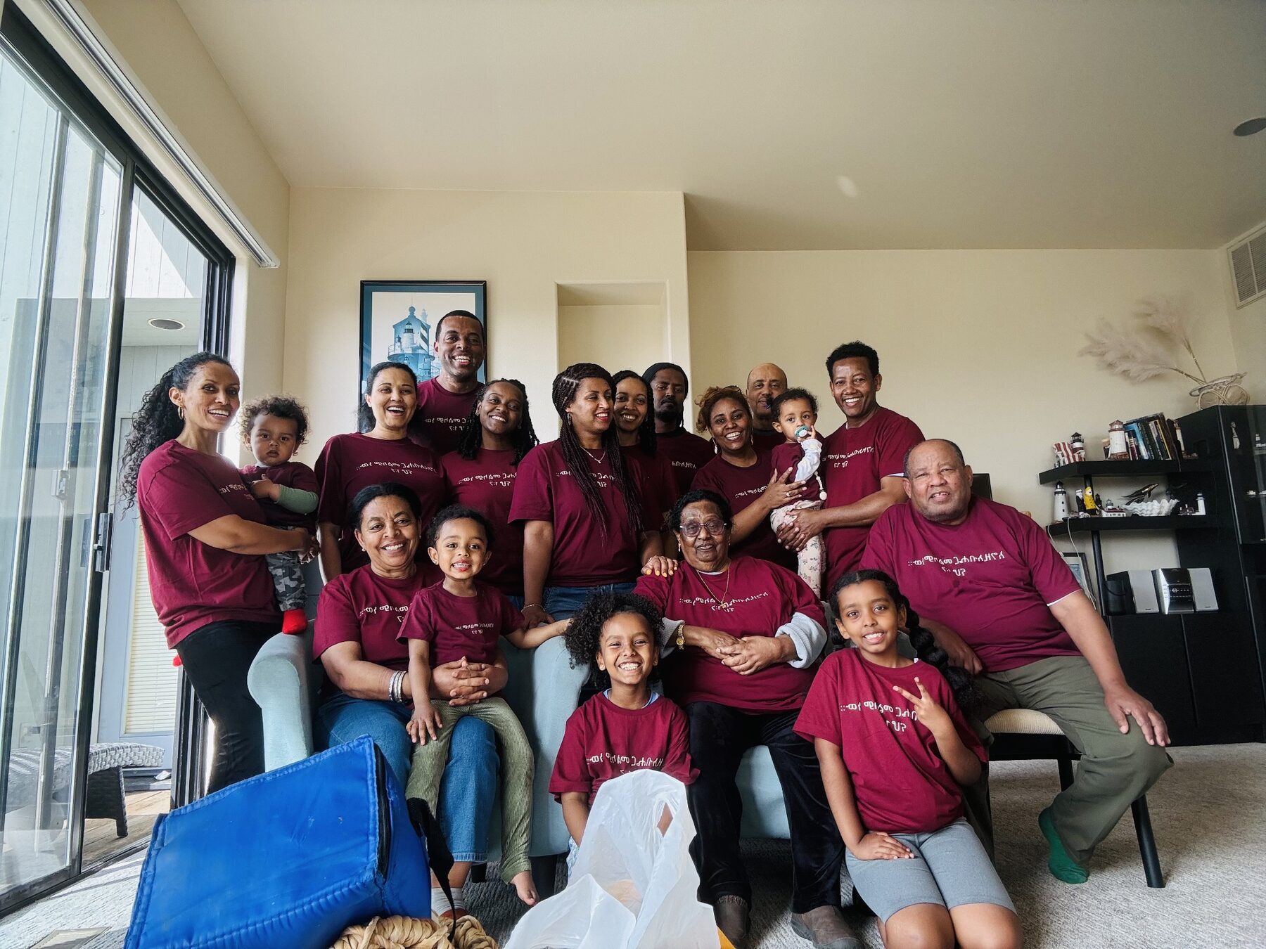 The extended family, all in matching maroon shirts, gathered together in a living room for a group portrait on a past family trip