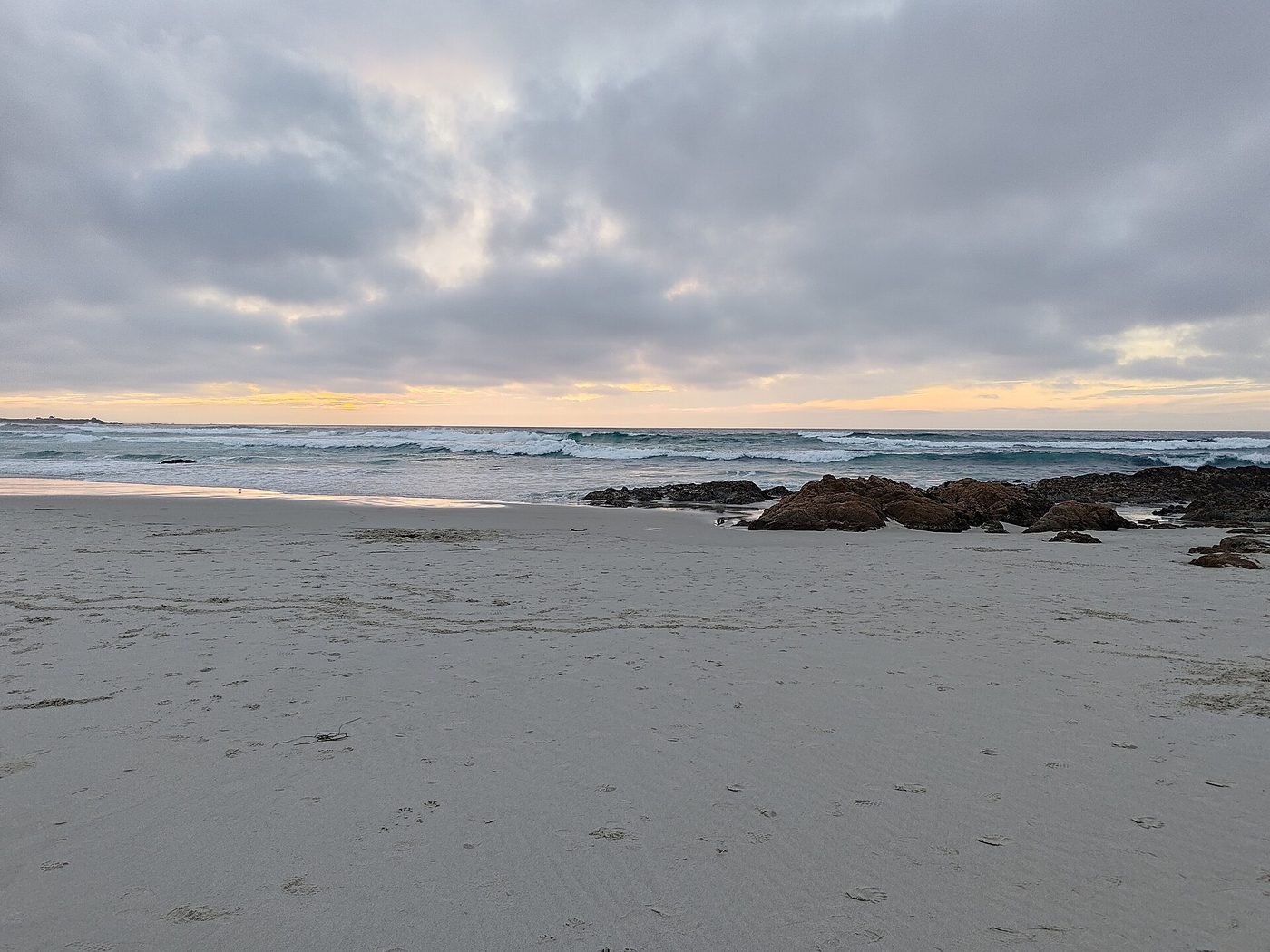 A quiet stretch of pale sand and low surf under soft grey coastal clouds at Asilomar State Beach