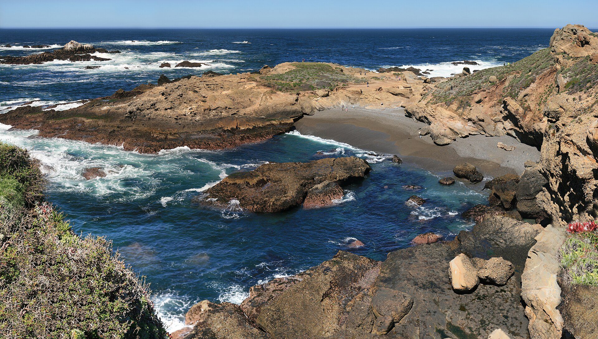 Rugged shoreline and deep blue water along the Monterey coast at Point Lobos, with cypress trees on the headland